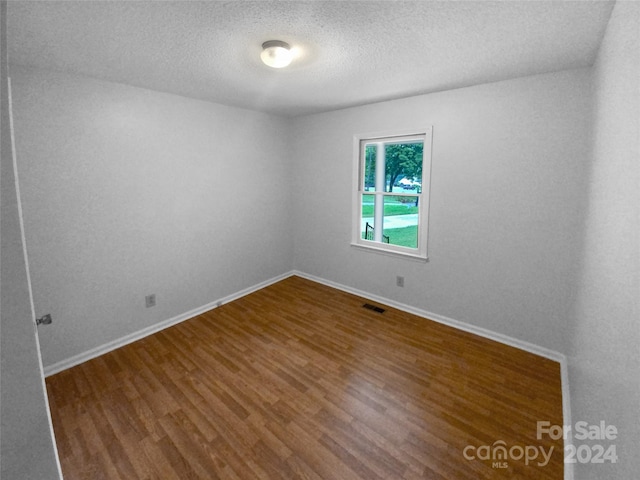 empty room featuring hardwood / wood-style flooring and a textured ceiling