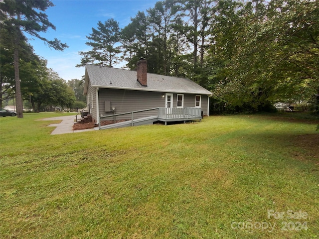 rear view of house with a deck and a yard