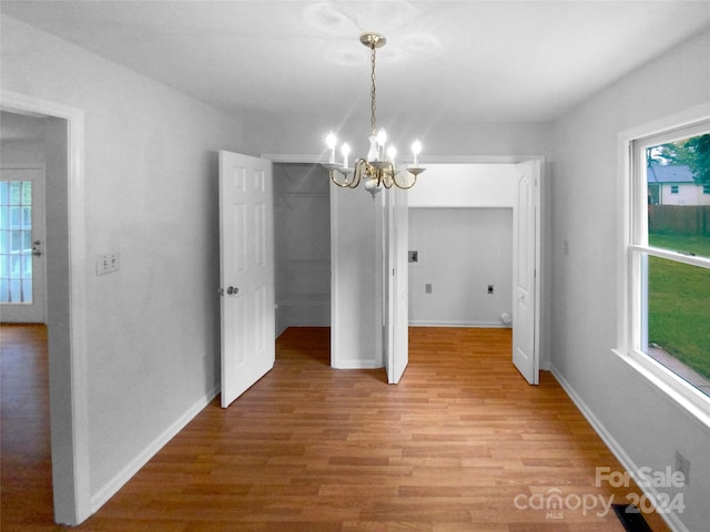 unfurnished dining area featuring wood-type flooring, a chandelier, and a healthy amount of sunlight