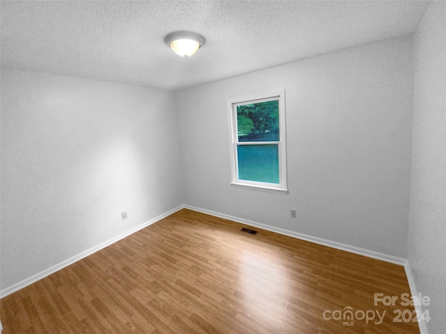 unfurnished room featuring a textured ceiling and hardwood / wood-style floors