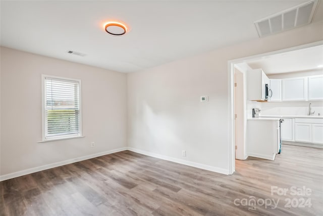 unfurnished room with light hardwood / wood-style floors and sink