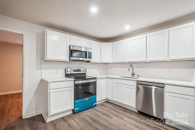 kitchen featuring white cabinets, appliances with stainless steel finishes, light wood-type flooring, and sink