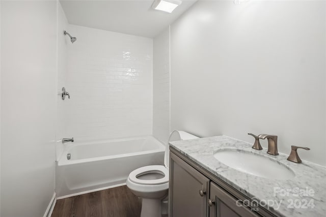 full bathroom featuring vanity, tiled shower / bath, hardwood / wood-style flooring, and toilet