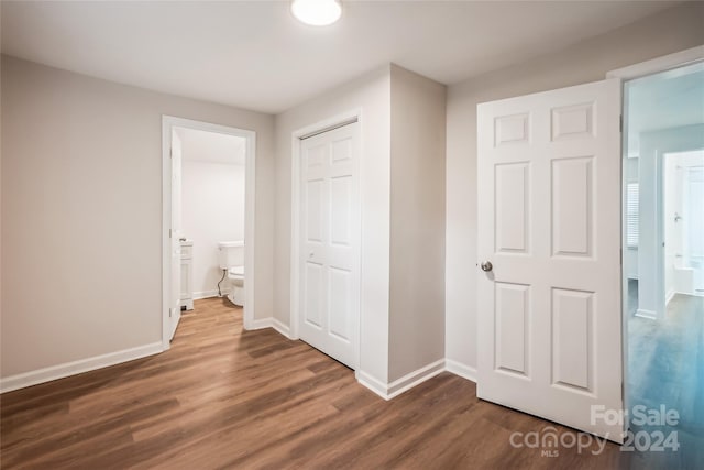 unfurnished bedroom featuring connected bathroom, dark hardwood / wood-style floors, and a closet