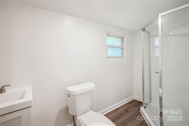 bathroom featuring wood-type flooring, vanity, a shower with shower door, and toilet