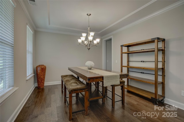 dining room with a chandelier, ornamental molding, a tray ceiling, and dark wood-type flooring