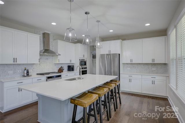 kitchen featuring sink, white cabinets, stainless steel appliances, and wall chimney range hood