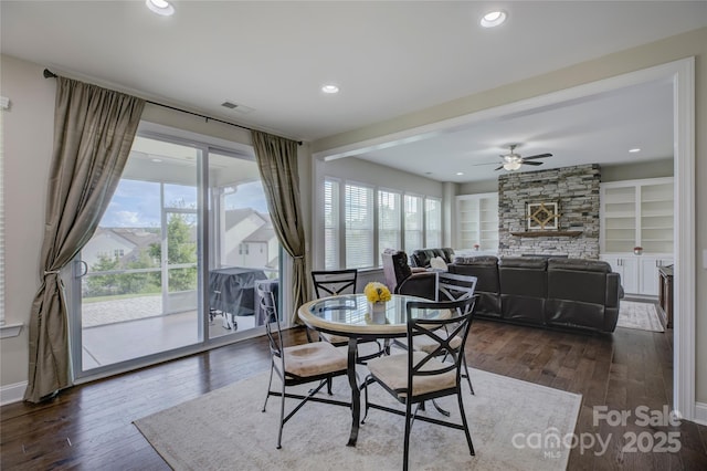 dining room featuring built in shelves, ceiling fan, dark hardwood / wood-style flooring, and a fireplace