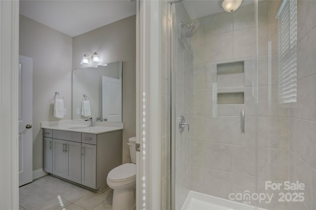 bathroom with tile patterned flooring, vanity, toilet, and walk in shower