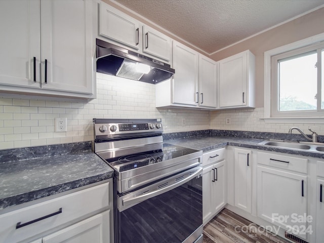 kitchen with decorative backsplash, stainless steel electric range, white cabinets, hardwood / wood-style flooring, and sink