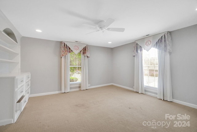 empty room with light carpet, ceiling fan, and a wealth of natural light