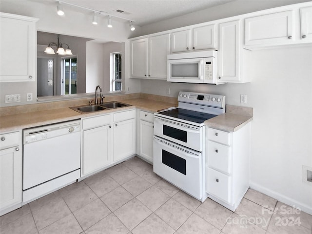 kitchen featuring light tile patterned flooring, hanging light fixtures, sink, white appliances, and white cabinetry