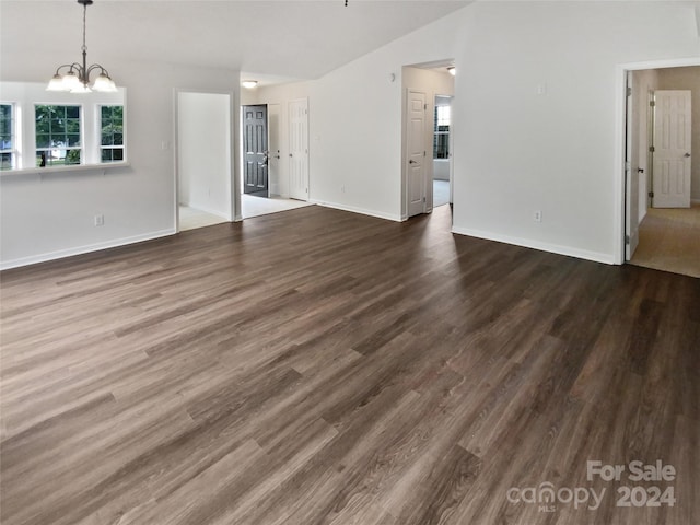 unfurnished living room with dark hardwood / wood-style floors and a notable chandelier