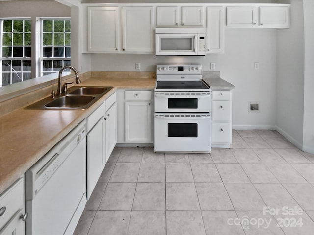 kitchen with white appliances, light tile patterned flooring, sink, and white cabinets