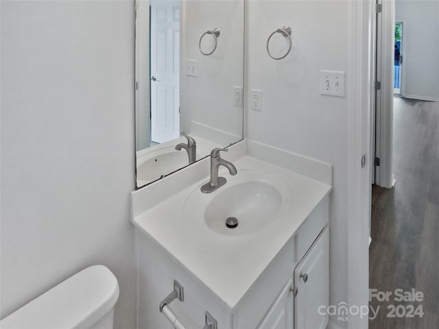 bathroom with hardwood / wood-style flooring, vanity, and toilet