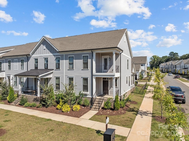 view of front of house featuring a balcony, a porch, and a front lawn