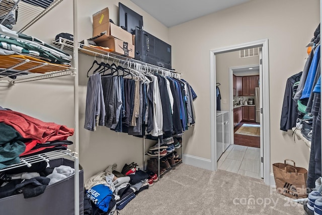 walk in closet with separate washer and dryer and light carpet