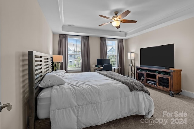 carpeted bedroom featuring ceiling fan and a raised ceiling