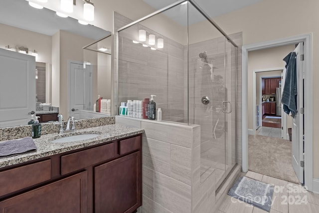 bathroom featuring tile patterned flooring, a shower with door, and vanity