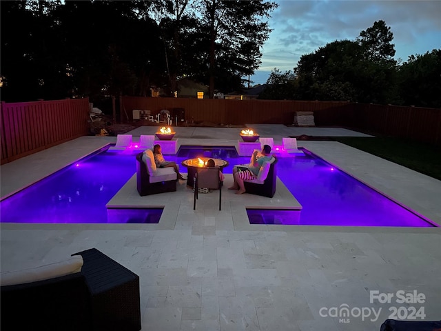 pool at dusk featuring a patio area and a fire pit