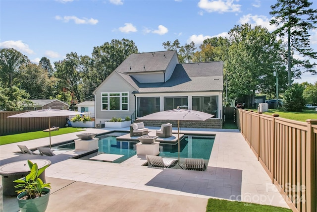 rear view of house with outdoor lounge area, a patio area, a fenced in pool, and a sunroom