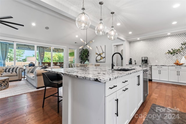 kitchen featuring tasteful backsplash, sink, dark wood-type flooring, and an island with sink