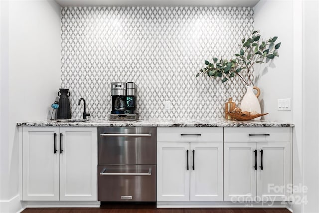 bar featuring light stone countertops, sink, and white cabinets