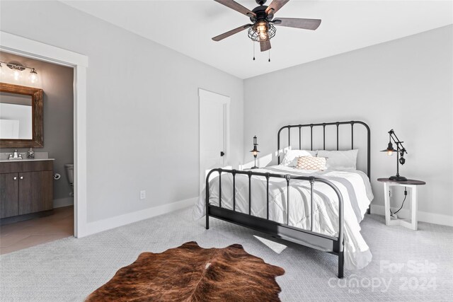 carpeted bedroom with ensuite bathroom, sink, and ceiling fan