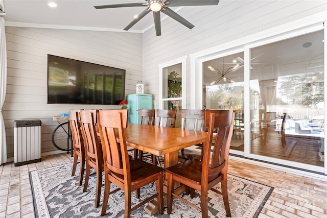 dining room with ceiling fan, high vaulted ceiling, and wood walls