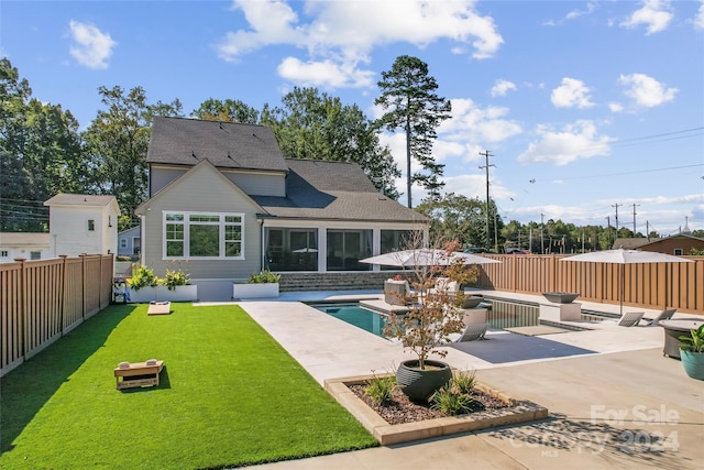 rear view of house with a yard, a patio area, and a fenced in pool