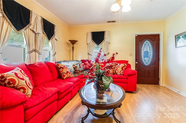 living room with a textured ceiling, hardwood / wood-style flooring, plenty of natural light, and crown molding