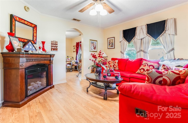 living room with crown molding, ceiling fan, wood-type flooring, and a textured ceiling