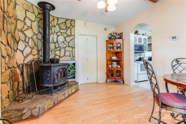 office space featuring a textured ceiling, light hardwood / wood-style floors, a wood stove, and ornamental molding