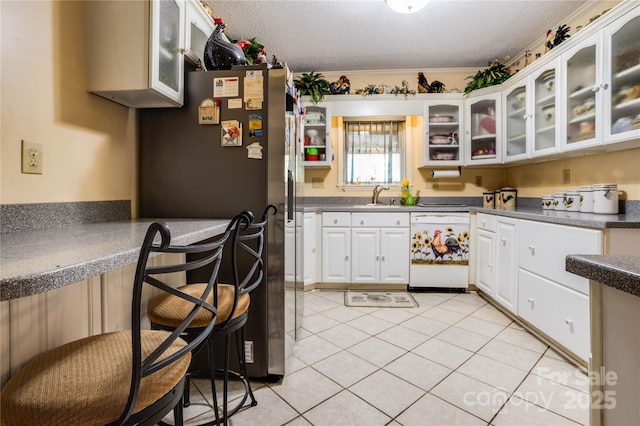 kitchen with white dishwasher, white cabinets, sink, and a textured ceiling