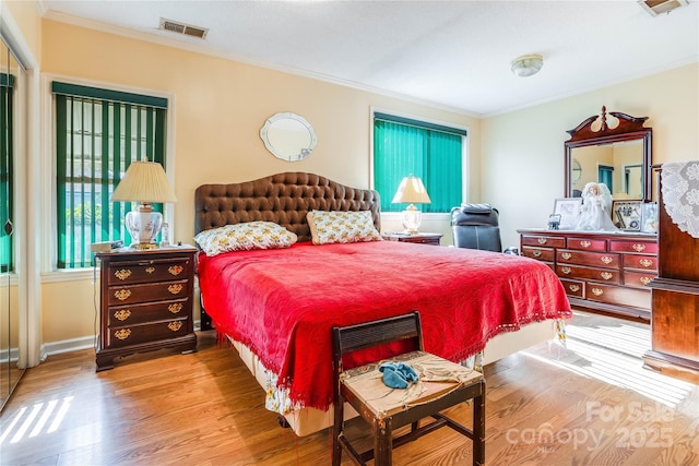 bedroom with multiple windows, crown molding, and wood-type flooring