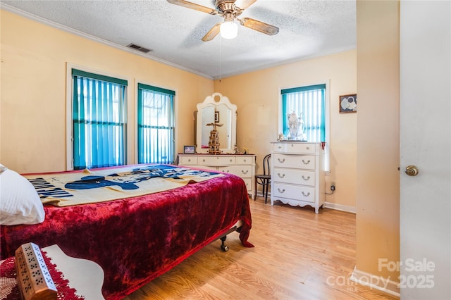 bedroom with multiple windows, ceiling fan, light hardwood / wood-style floors, and a textured ceiling