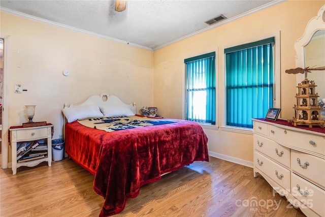 bedroom with a textured ceiling, light hardwood / wood-style floors, ceiling fan, and crown molding