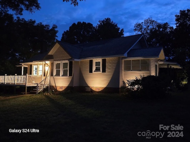 property exterior at dusk with a deck and a yard