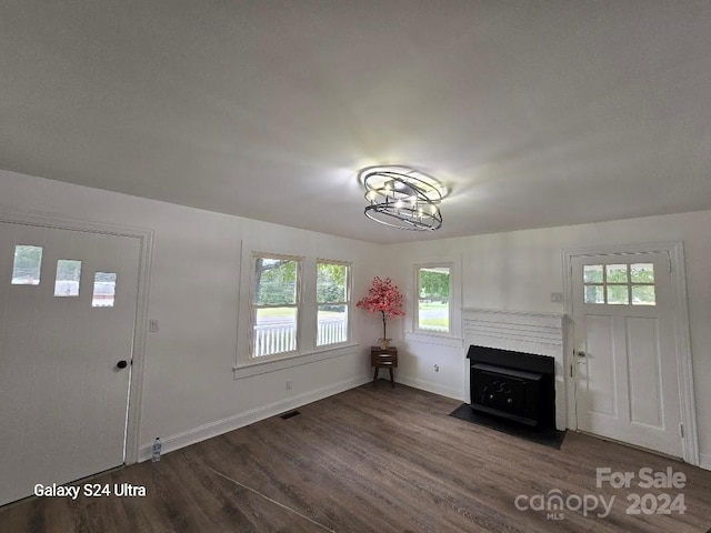 unfurnished living room featuring an inviting chandelier, dark hardwood / wood-style floors, and a wealth of natural light