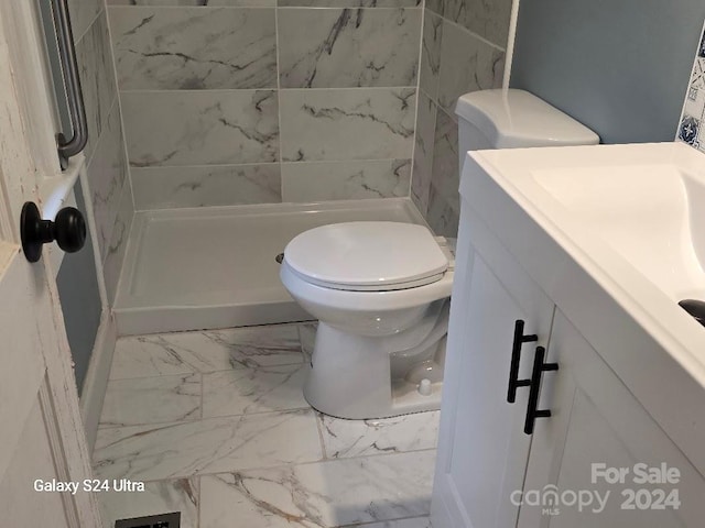 bathroom featuring a tile shower, vanity, and toilet