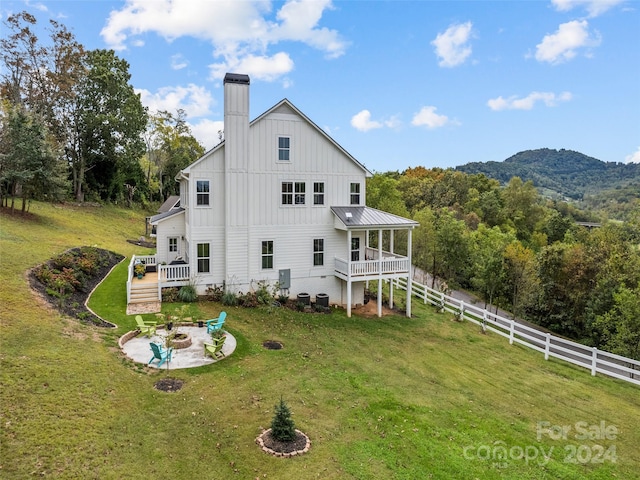 back of property featuring a lawn, a fire pit, and a mountain view