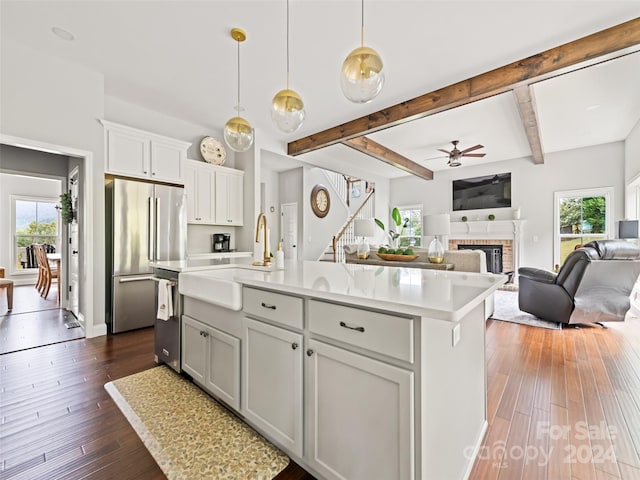 kitchen featuring stainless steel appliances, a wealth of natural light, dark hardwood / wood-style floors, and a center island with sink