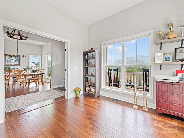 interior space with a mountain view, wood-type flooring, a healthy amount of sunlight, and a notable chandelier