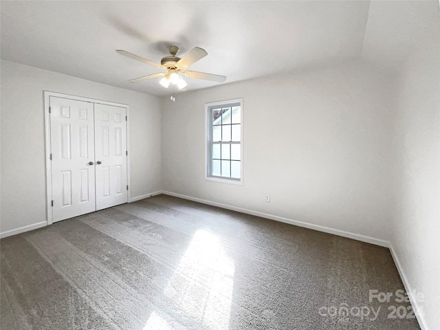 unfurnished bedroom featuring carpet floors, vaulted ceiling, ceiling fan, and a closet