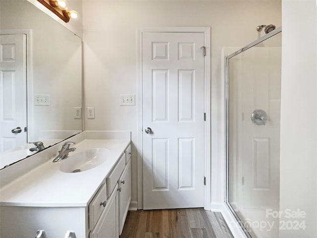 bathroom with wood-type flooring, a shower with door, and vanity