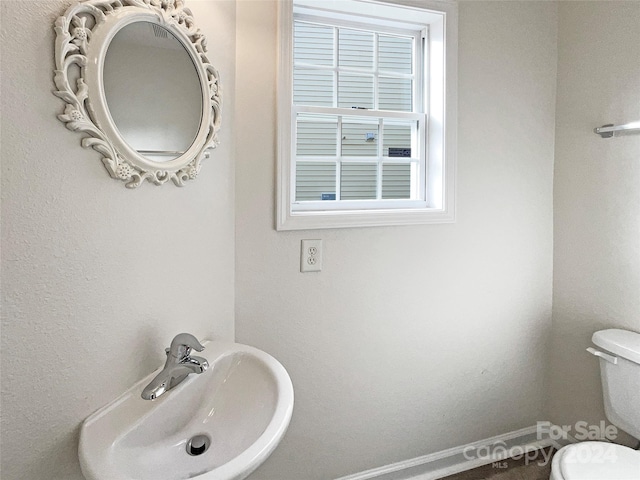 bathroom with toilet, sink, and plenty of natural light