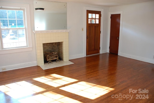 unfurnished living room with dark hardwood / wood-style floors and a tile fireplace