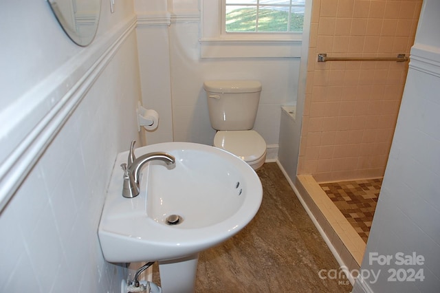 bathroom with sink, toilet, and tiled shower