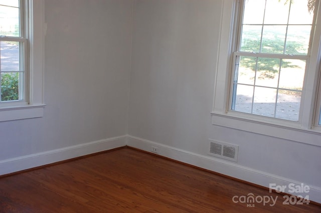 unfurnished room with plenty of natural light and dark wood-type flooring