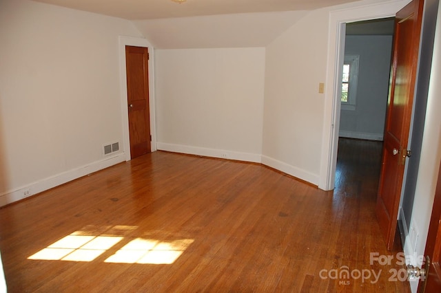 empty room with lofted ceiling and hardwood / wood-style flooring